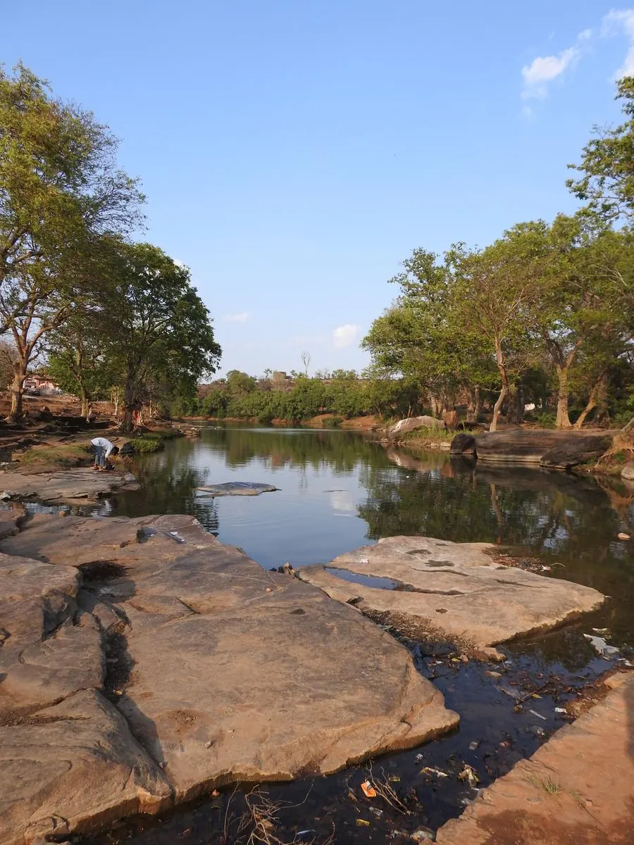 Calm river with flat sandstone rocks and tree reflections