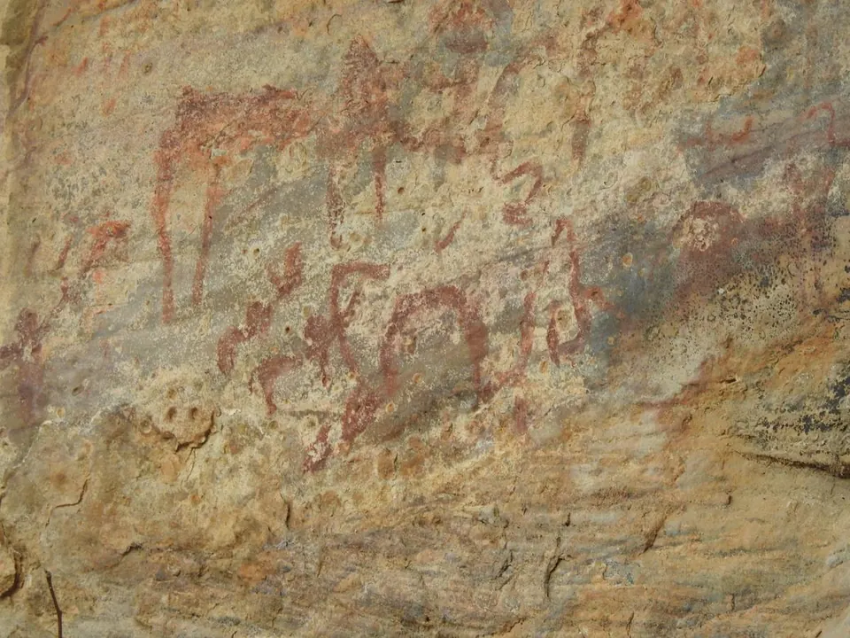 Rock art panel with human and animal figures in red pigment